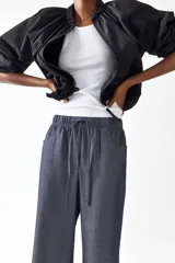 Pantalón recto de corte holgado con cintura elástica de tiro alto y cordón ajustable. Presenta bolsillos delanteros y traseros abiertos.