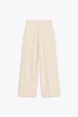 Pantalón de lino negro, de tiro alto, con bolsillos delanteros de vivo, pernera recta y cierre frontal con cremallera, botón interior y gancho metálico.