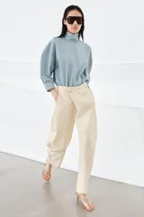 Pantalón de tiro medio confeccionado en algodón, con diseño cruzado en la cintura y cierre frontal con botones. Presenta trabillas para cinturón, bolsillos laterales ocultos y un bolsillo frontal con solapa y botón.