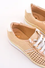 Zapatillas acordonadas color dorado con capellada de cuero calado, base blanca y detalles en cuero blanco en el talón.