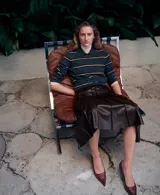 Falda midi plisada de cuero sintético en color marrón oscuro, con diseño acampanado y talle alto.