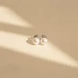 Aros tipo caravana con perlas de río blancas y base de plata 925 con detalle de engarce texturizado.