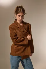 Blazer de gamuza color marrón con cuello solapa, corte holgado y detalle de tachas metálicas en solapas, bolsillos delanteros y puños.