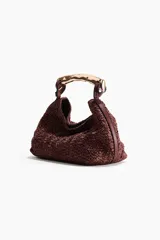 Bolso de mano de textura rugosa color bordó, con asa rígida de metal dorado de diseño ondulado y cierre magnético.