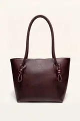 Cartera tote de cuero suave color bordó, con diseño amplio, líneas simples y asas de hombro con detalles de nudos hechos a mano.
