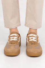 Zapatilla deportiva estilo urbano de corte bajo, color verde con suela de goma marrón y cordones oscuros.