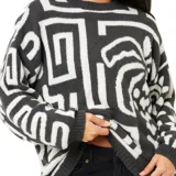 Buzo de tejido de punto con diseño estampado de palmeras y formas geométricas en contraste blanco y negro, cuello redondo y mangas largas.