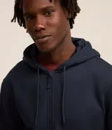 Buzo deportivo negro con capucha, cierre frontal con cremallera, bolsillos laterales y puños ajustados. Confeccionado en tejido de algodón y poliéster.