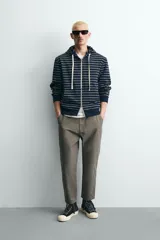 Pantalón de corte carrot fit confeccionado en tejido de algodón con estructura diagonal y efecto lavado. Presenta bolsillos frontales con bolsillo cerillero, bolsillos traseros de plastrón y cierre frontal con cremallera y botón.