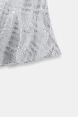 Top de tejido mesh con aplicación de strass, diseño de hombros descubiertos y escote drapeado. Presenta un corte ajustado y cierre lateral con cremallera oculta.