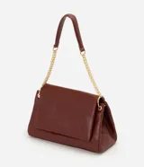 Cartera tipo shoulder bag de tamaño grande, confeccionada en poliuretano con textura de efecto croco. Presenta una solapa frontal con cierre magnético, herrajes en tono dorado claro y una correa de cadena metálica. Incluye un bolsillo interno con cremallera.