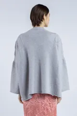 Sweater gris de punto con cuello redondo, mangas amplias y terminaciones acanaladas.