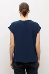 Blusa blanca con textura plumeti, de manga corta y cuello redondo.