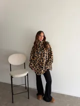 Buzo de peluche con estampado animal print de leopardo, cuello alto con cierre frontal parcial y tirador metálico, y diseño oversize de mangas largas.