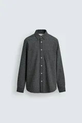 Camisa de corte regular fit confeccionada en una mezcla de lana y algodón. Presenta un diseño de cuadros pequeños, cuello solapa, manga larga con puños abotonados y cierre frontal con botones. Incluye un bolsillo en el pecho.