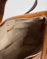 Cartera tipo tote bag color habano, combinando cuerpo de tejido texturizado tipo red y detalles en cuero sintético con costuras en contraste. Cuenta con doble asa corta de mano y correa larga ajustable y desmontable. Incluye aplique metálico con el logo de la marca en el frente.