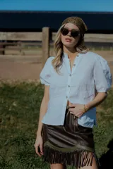 Minifalda marrón de cuero ovino con flecos y cierre frontal.