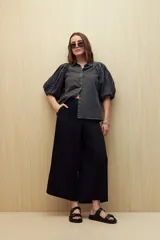 Pantalón de lino color negro, de tiro alto y corte wide leg con pierna ancha y caída fluida.