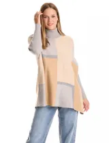 Polera tipo poncho de corte oversize, con cuello alto tejido y mangas largas con puños elásticos. Presenta un diseño geométrico de bloques de color en tonos beige, gris y tostado.