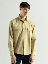 Camisa verde militar de manga larga, con cuello clásico, cierre con botones y dos bolsillos con solapa en el pecho.