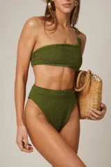 Conjunto de bikini negro asimétrico, con un solo hombro y detalle de argolla en el hombro derecho. La parte inferior es de corte alto a la cintura con faja ancha con elástico suave.
