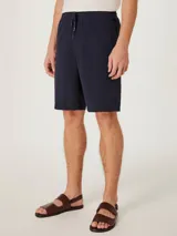 Bermuda azul marino de corte clásico y diseño liso, con bolsillos laterales y traseros.