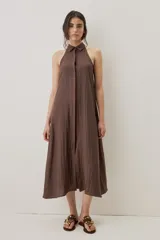 Vestido midi color marrón chocolate, con cuello camisero y abotonadura frontal oculta, escote halter y diseño sin mangas con silueta evasé.