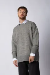 Sweater oversize de tejido de punto en color gris, con cuello redondo, puños y ruedo acanalados con detalles de desgaste. Presenta un diseño minimalista con logo tejido en la espalda.