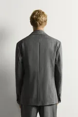 Blazer de corte relaxed fit de Zara, confeccionado en 100% lana color gris. Cuenta con cuello de solapas de muesca, manga larga, bolsillos de parche en la cadera, bolsillo de vivo en el pecho y cierre frontal con un botón.