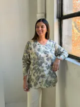 Sweater de punto con estampado animal print en tonos verde claro y gris sobre fondo beige, de cuello redondo y manga larga.