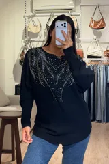 Buzo tejido de punto color negro, con diseño de brillos aplicados en la parte superior delantera, cuello redondo y mangas largas.