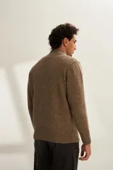 Campera tejida color marrón claro con cierre delantero, cuello alto y bolsillos delanteros. Tejida en 100% lana fina sin teñir.