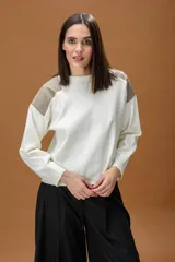 Sweater de punto color blanco con cuello redondo y detalles en cuero sintético color beige en los hombros. Presenta mangas largas con puños acanalados y un corte holgado.