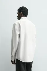 Camisa de corte relajado confeccionada en tejido fluido de lyocell. Presenta cuello solapa, manga larga con puños abotonados y cierre frontal con botones.