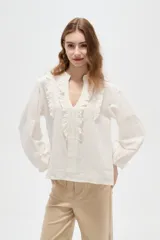 Blusa de viscosa color blanco, con cuello en V, detalles de volados y frunces en el frente, y mangas largas abullonadas con puños ajustados.