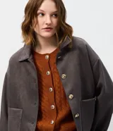 Campera de gamuza sintética color tostado con botones dorados grabados, cuello camisero, bolsillos frontales aplicados y mangas largas con puños abotonados.