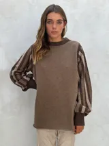 Sweater de lana color marrón, con cuerpo liso y mangas abullonadas con diseño de rayas horizontales en tonos marrón claro y oscuro. Cuello redondo y puños acanalados.