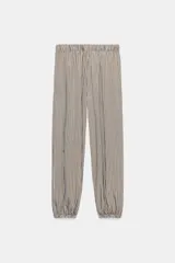 Pantalón de tiro medio con pierna ancha y cintura elástica, confeccionado en mezcla de viscosa con diseño de rayas verticales en tonos mostaza y marrón.