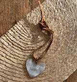 Gargantilla con dije de corazón de guampa y tiento de cuero marrón.