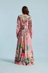 Vestido largo Natalia Antolin de color rosado con estampado floral y de aves, escote en V profundo, mangas largas abullonadas con puños y lazo ajustable en la cintura.
