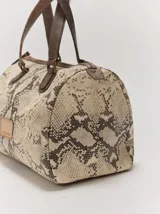 Cartera tipo baúl Margara Shaw confeccionada en 100% cuero con estampado animal print de serpiente, asas de mano marrones y cierre superior.