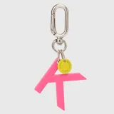 Llavero con dije en forma de letra A color rosado y pequeño dije circular amarillo con logo de la marca grabado. Incluye gancho metálico tipo mosquetón.