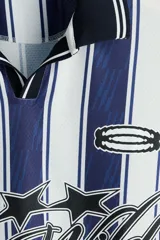 Camiseta de fútbol de manga larga confeccionada en malla estampada, con diseño de rayas verticales en azul marino y blanco. Presenta cuello polo negro con ribete blanco, cierre frontal parcial en V, y puños elásticos negros con líneas blancas. Cuenta con estampado frontal con gráficos de estrellas y la inscripción "Run Wild".