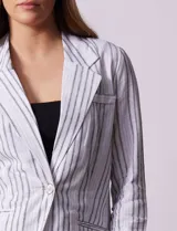 Blazer blanco con rayas verticales negras, cuello con solapa, abertura central con botón y bolsillos delanteros.