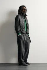 Cazadora regular fit de Zara en colaboración con Aaron Levine, confeccionada en tejido de algodón con acabado efecto encerado en color negro. Presenta cuello subido, manga larga con puño ajustable, bolsillos frontales con solapa y cierre de cremallera oculto con solapa de botones a presión.