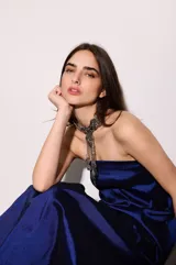 Vestido largo azul con escote strapless, corte suelto y fluido, confeccionado en tafeta con efecto tornasolado, y bolsillos ocultos en los laterales.