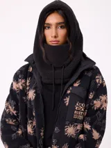 Pasamontañas de tejido tipo corderito sintético en color negro, con diseño de capucha integrada y cordones ajustables en la parte frontal.