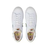 Championes Nike Blazer Low Platform Next Nature, de diseño bajo con plataforma. Presentan un cuerpo de lona blanca con detalles en cuero texturizado, un swoosh lateral en color celeste y un pequeño parche bordado decorativo. Incluyen refuerzos en la puntera y el talón en tonos neutros.