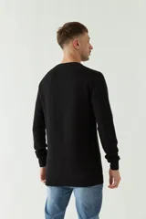 Sweater negro de punto con textura acanalada horizontal, cuello redondo y logo bordado en el pecho.