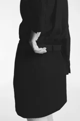 Pollera mini de tiro alto, confeccionada en tela lisa, con cierre lateral oculto y cinturón extraíble con hebilla metálica plateada.